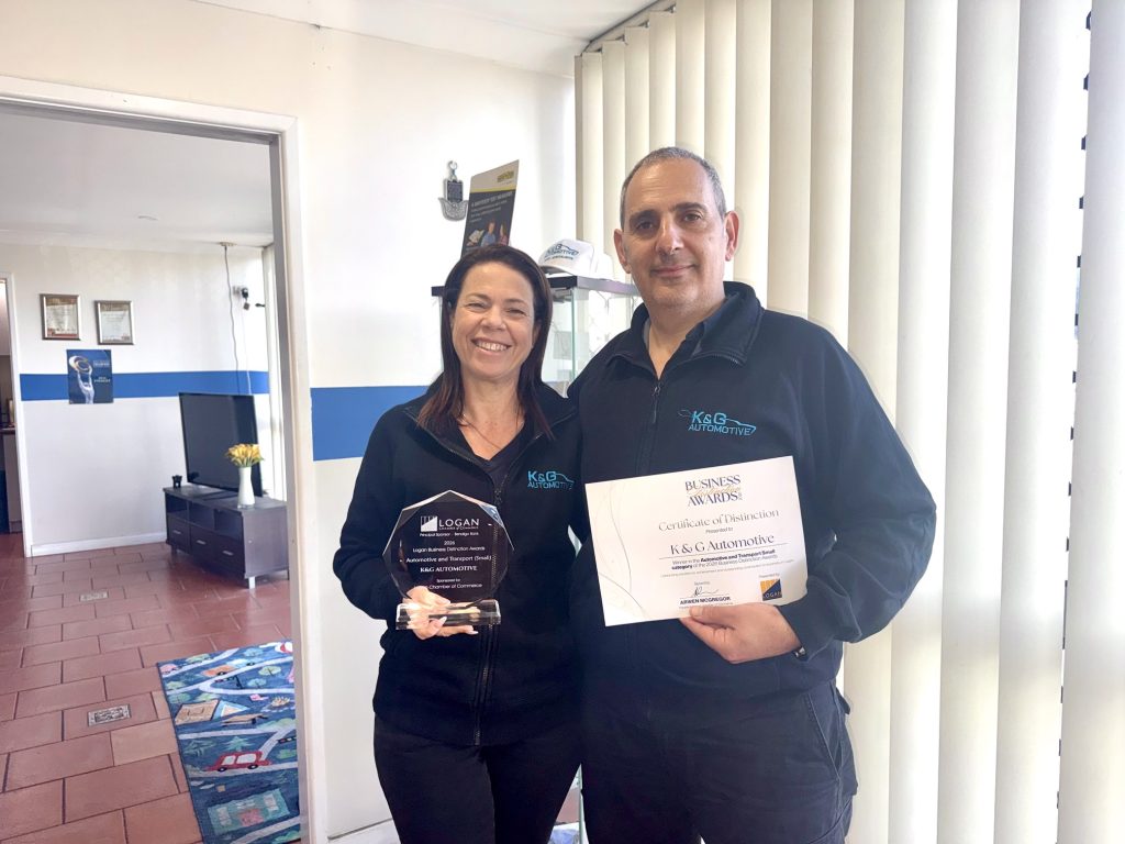 Einat and Shlomi Kuba holding the 2026 Logan Business Distinction Awards trophy and Certificate of Distinction for the Automotive and Transport Small category at K&G Automotive in Underwood